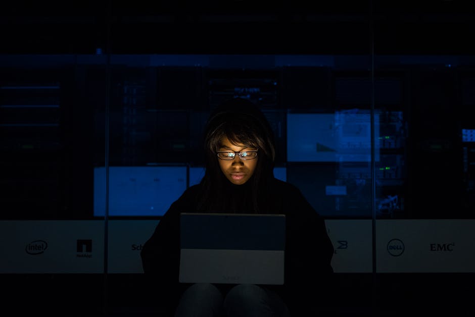 Person working on servers in a dimly lit data center, focused and problem-solving