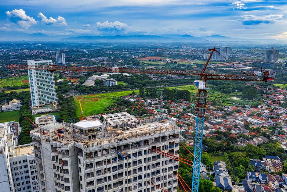 Aerial view of a half-finished suburban housing development, cranes idle, overcast sky, wide shot, photorealistic