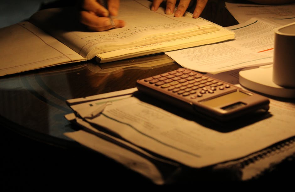 A person studying charts on a laptop at night, single lamp illuminating the desk, focused and determined atmosphere
