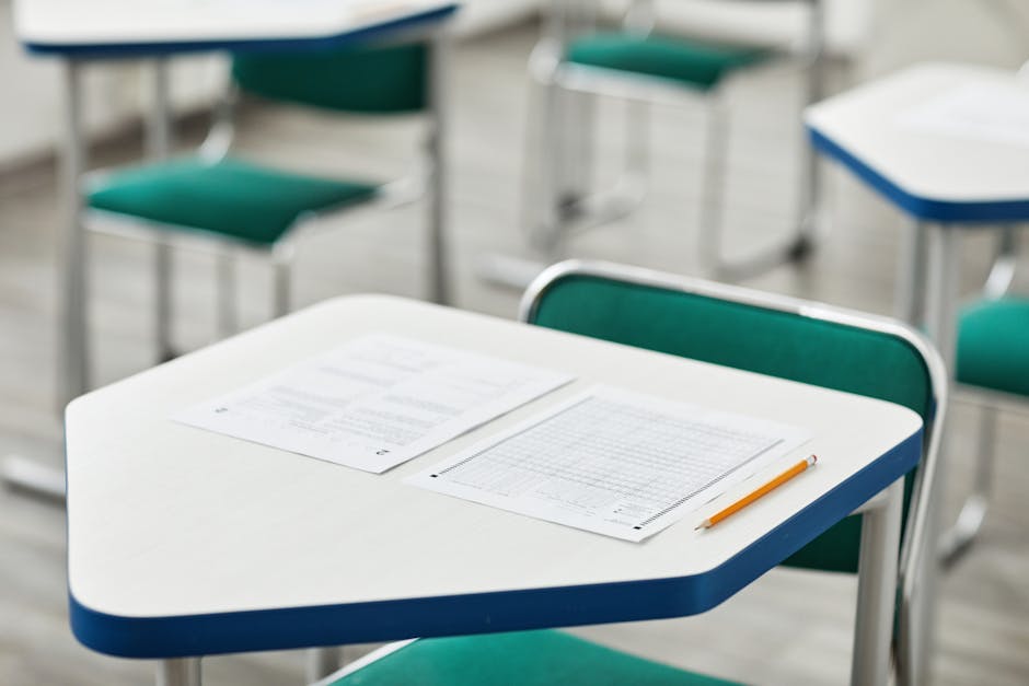 Empty classroom with rows of identical desks, fluorescent lighting, chalkboard with standardized test scores written on it, slightly dystopian atmosphere