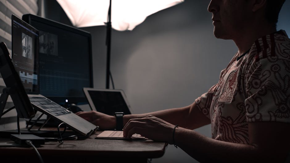 A person studying for IT certifications at a desk with multiple monitors, home lab servers visible in the background, warm focused lighting