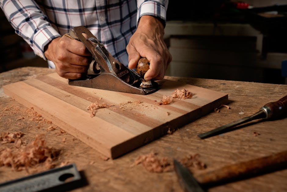 A weathered craftsman's workbench covered with wood shavings, hand tools, and a partially finished project under warm workshop lighting