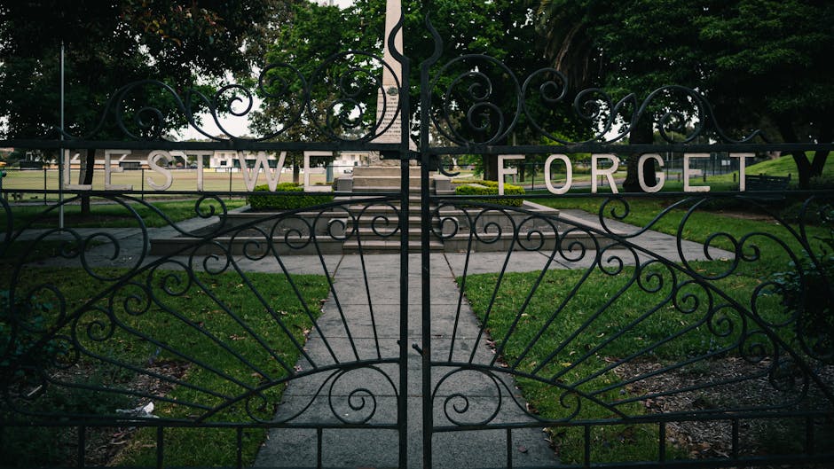 A heavy ornate iron gate standing alone in an open field with no fence attached to it, symbolizing pointless gatekeeping