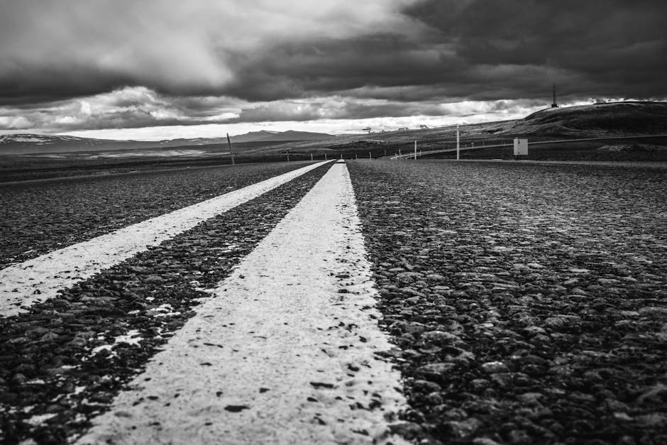 A winding road through a vast landscape leading toward a horizon with light breaking through clouds, metaphorical, wide angle, cinematic photography style