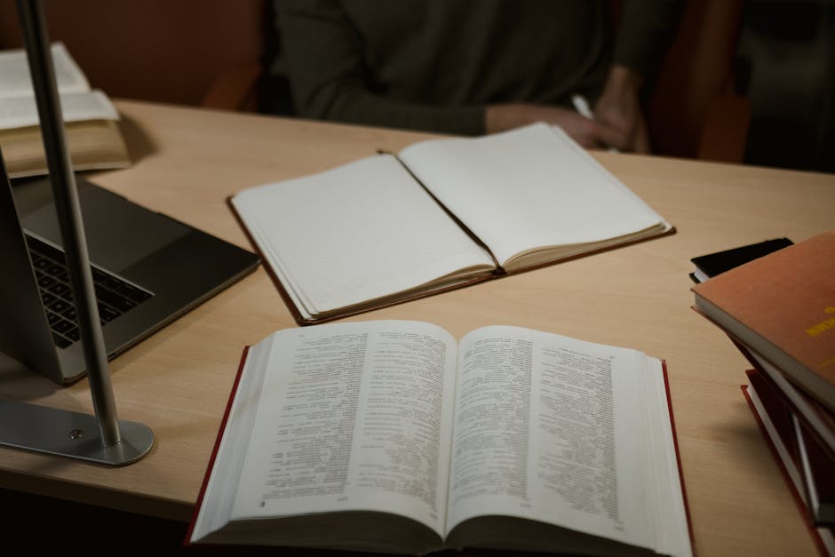A person hunched over a laptop with multiple browser tabs open, notebooks filled with handwritten notes scattered around, warm desk lamp lighting, cinematic and focused
