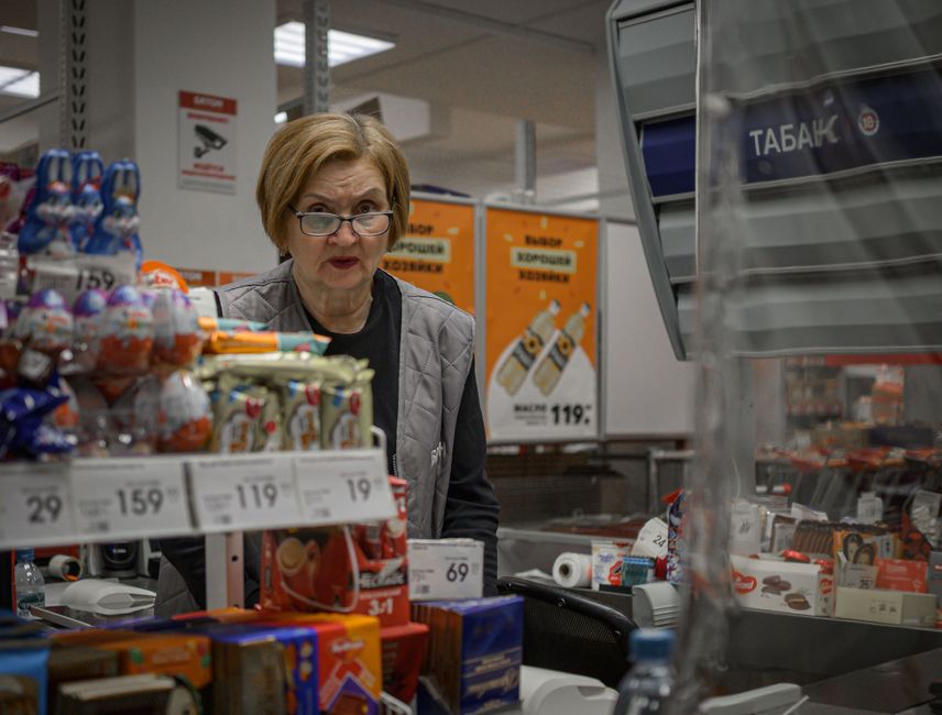 A person staring at a rising price tag in a grocery store, warm harsh lighting, realistic, slightly unsettling mood
