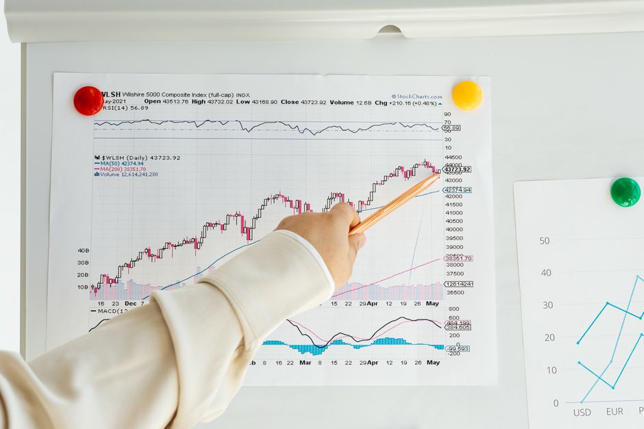 A whiteboard with economic graphs and numbers, a skeptical person studying them, moody blue office lighting, photorealistic