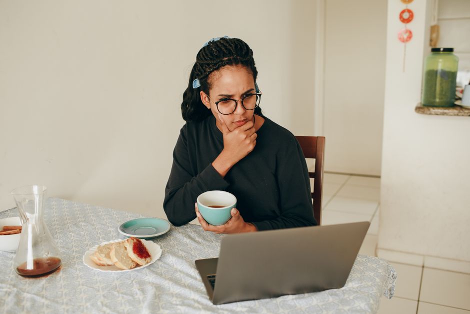 A person at a kitchen table with a laptop and coffee, calmly adjusting privacy settings—ordinary, not dramatic