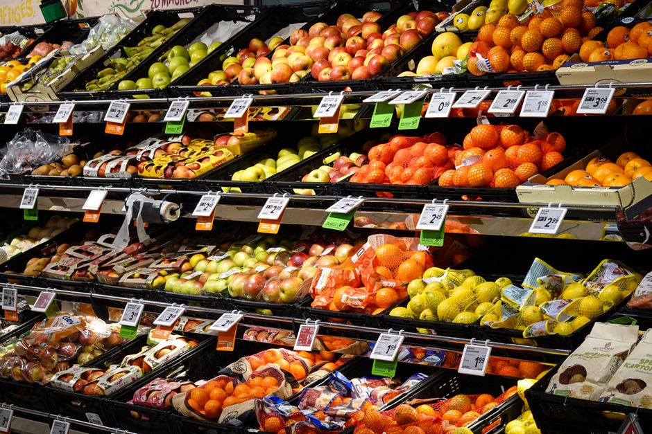 A grocery cart full of food with a price tag showing a dramatically higher number than expected, realistic photography, warm lighting