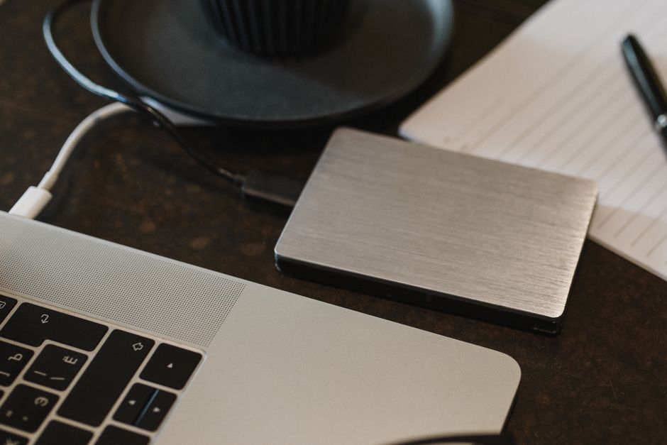 A calm desk with a hardware wallet, a notebook with handwritten private key backup instructions, and a cup of coffee — practical, grounded, no hype