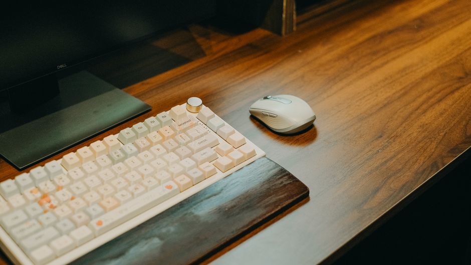 A clean minimal home office desk setup with a monitor, mechanical keyboard, and soft morning light — calm and intentional, not cluttered
