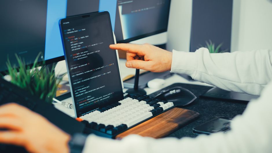 A developer at a desk reviewing AI-generated code suggestions on a split-screen monitor, thoughtful expression, realistic photo style
